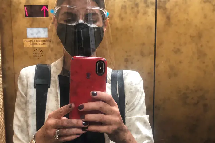 Legal Aid lawyer Anna Carlsen, dressed in a mask and face shield to meet a client in court, taking a selfie in the elevator.